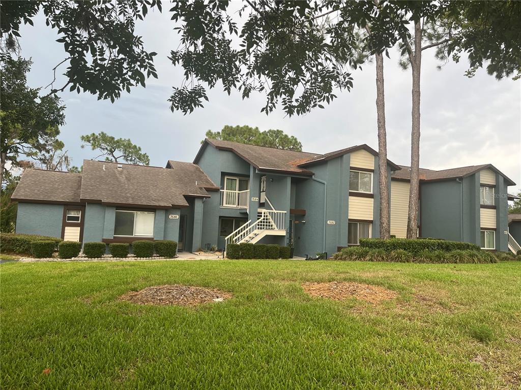 A two-story apartment building with blue siding, a brown roof, and an exterior staircase — 7686 ST ANDREWS BOULEVARD, WEEKI WACHEE, FL