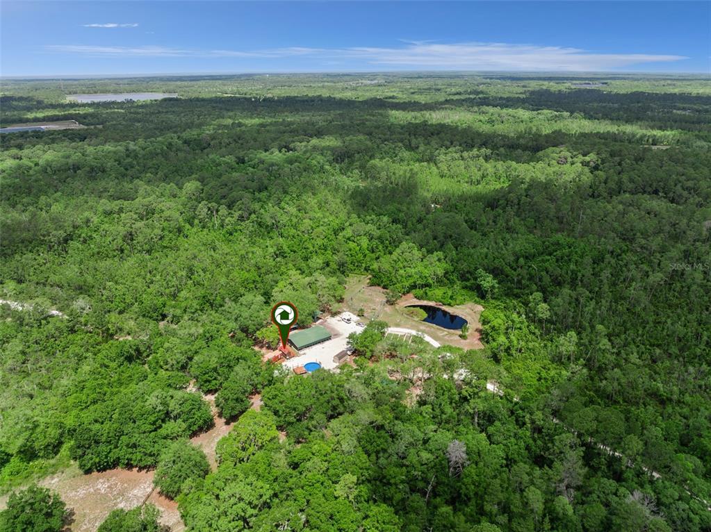 An aerial view shows a house with a pool and pond surrounded by dense forest — 1140 BUCKLES ROAD, PIERSON, FL