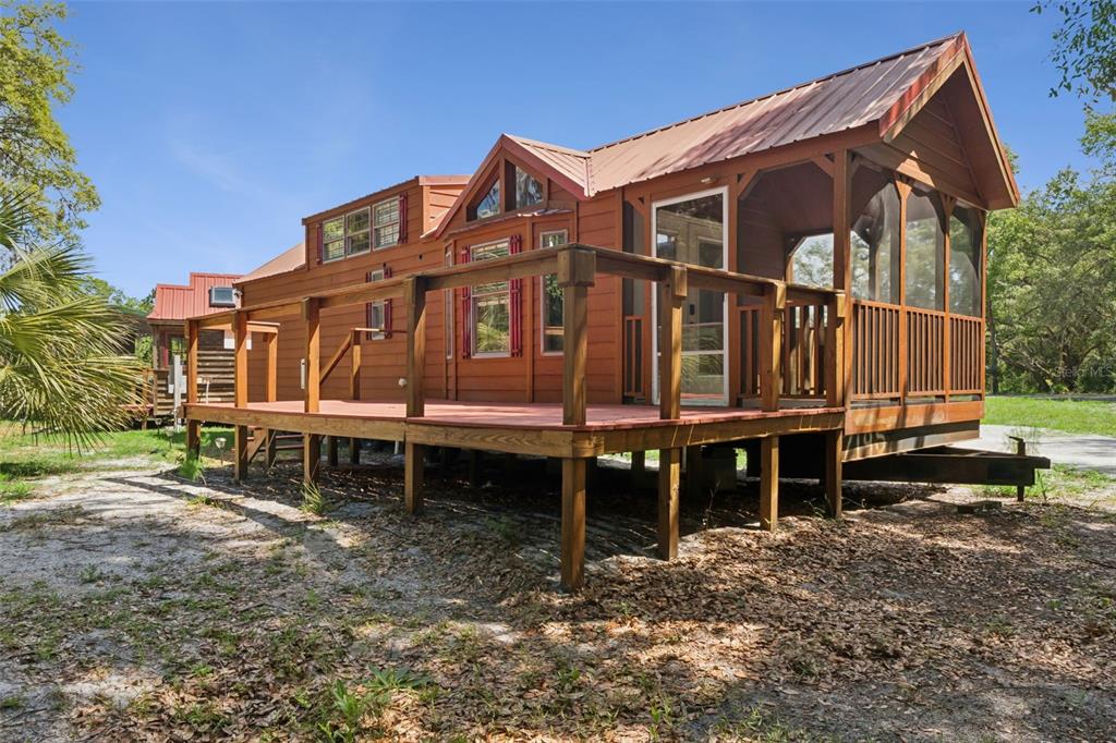 A wooden park model home with a metal roof and a large attached screened porch — 1140 BUCKLES ROAD, PIERSON, FL