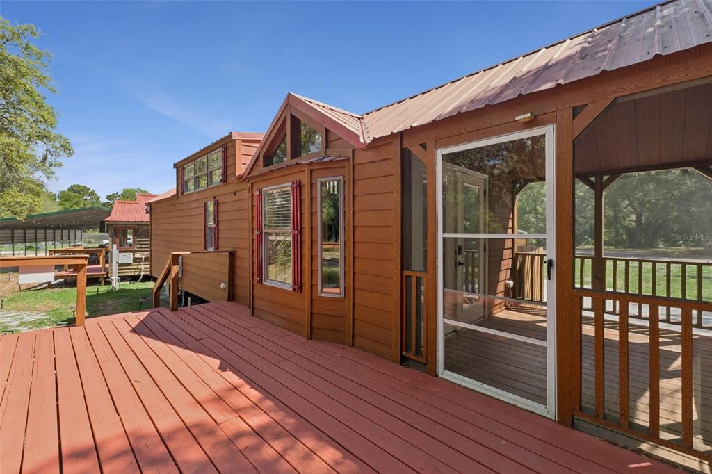 A wooden cabin features a large deck, a screened-in porch, and a metal roof — 1140 BUCKLES ROAD, PIERSON, FL