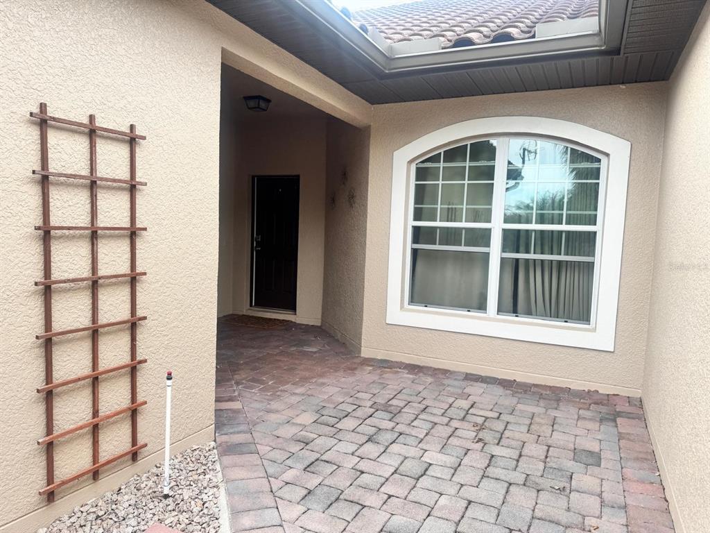 A paved entryway features a wooden trellis on the wall and a large arched window — 26715 BELLA VISTA DRIVE, HOWEY IN THE HILLS, FL