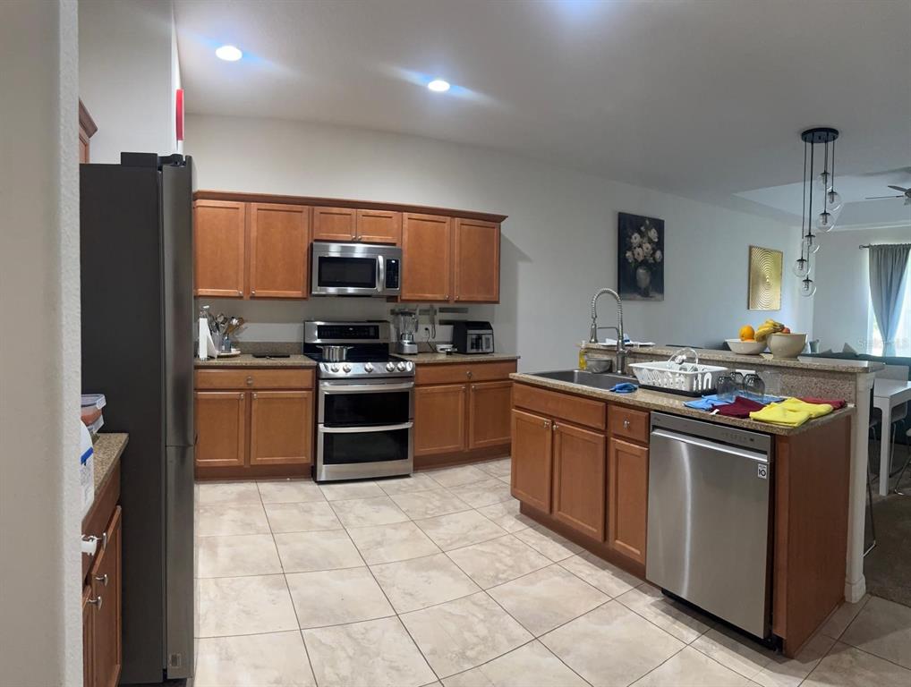 A kitchen features wood cabinets, stainless steel appliances, a tile floor, and a breakfast bar — 26715 BELLA VISTA DRIVE, HOWEY IN THE HILLS, FL