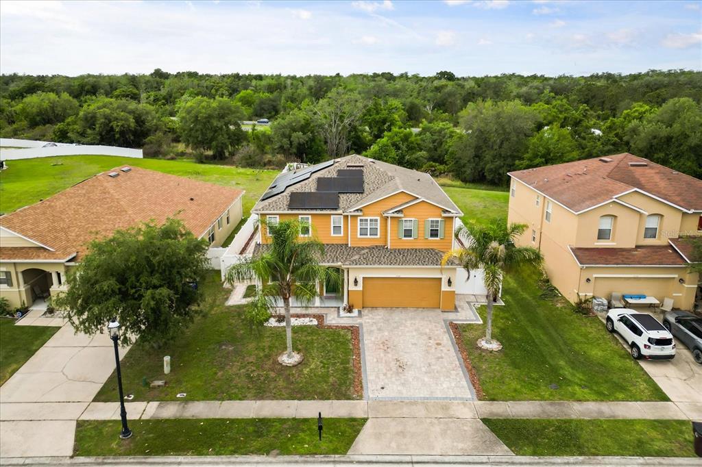 An aerial view of a two-story suburban house with solar panels on the roof — 3332 WHISTLING TRAIL, ST CLOUD, FL