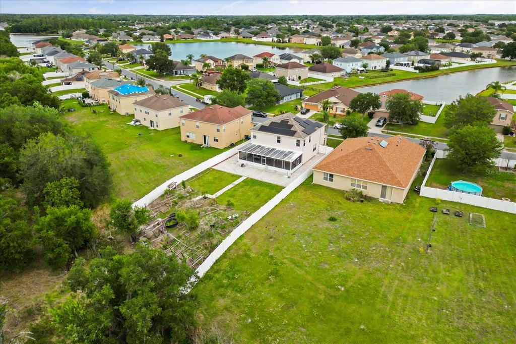 An aerial view shows a two-story house with solar panels and a large backyard — 3332 WHISTLING TRAIL, ST CLOUD, FL