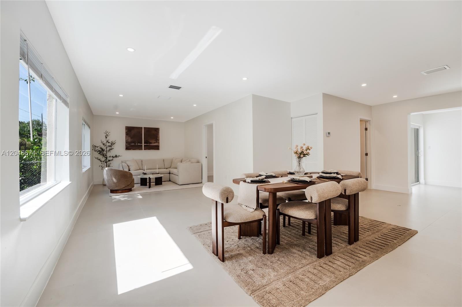A dining area with a wooden table and chairs sits in front of a living room — 8318 NE 3rd Ct, Miami FL 33138, MIAMI, FL