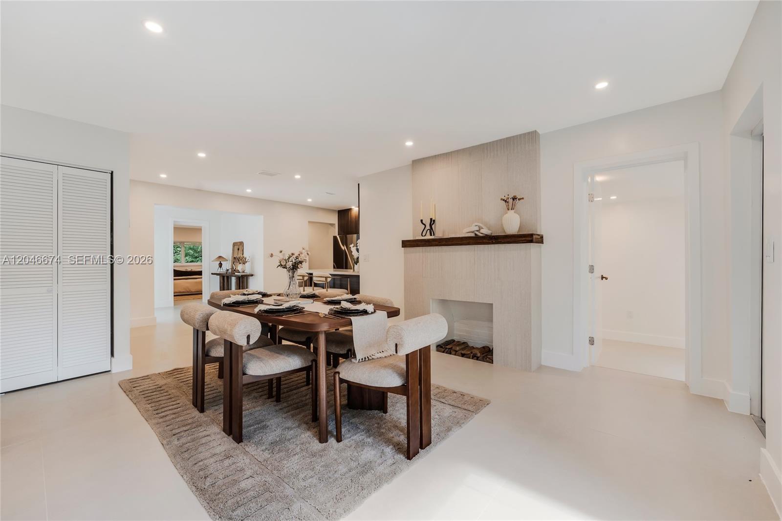 A dining room features a wooden table, upholstered chairs, a fireplace, and light-colored flooring — 8318 NE 3rd Ct, Miami FL 33138, MIAMI, FL