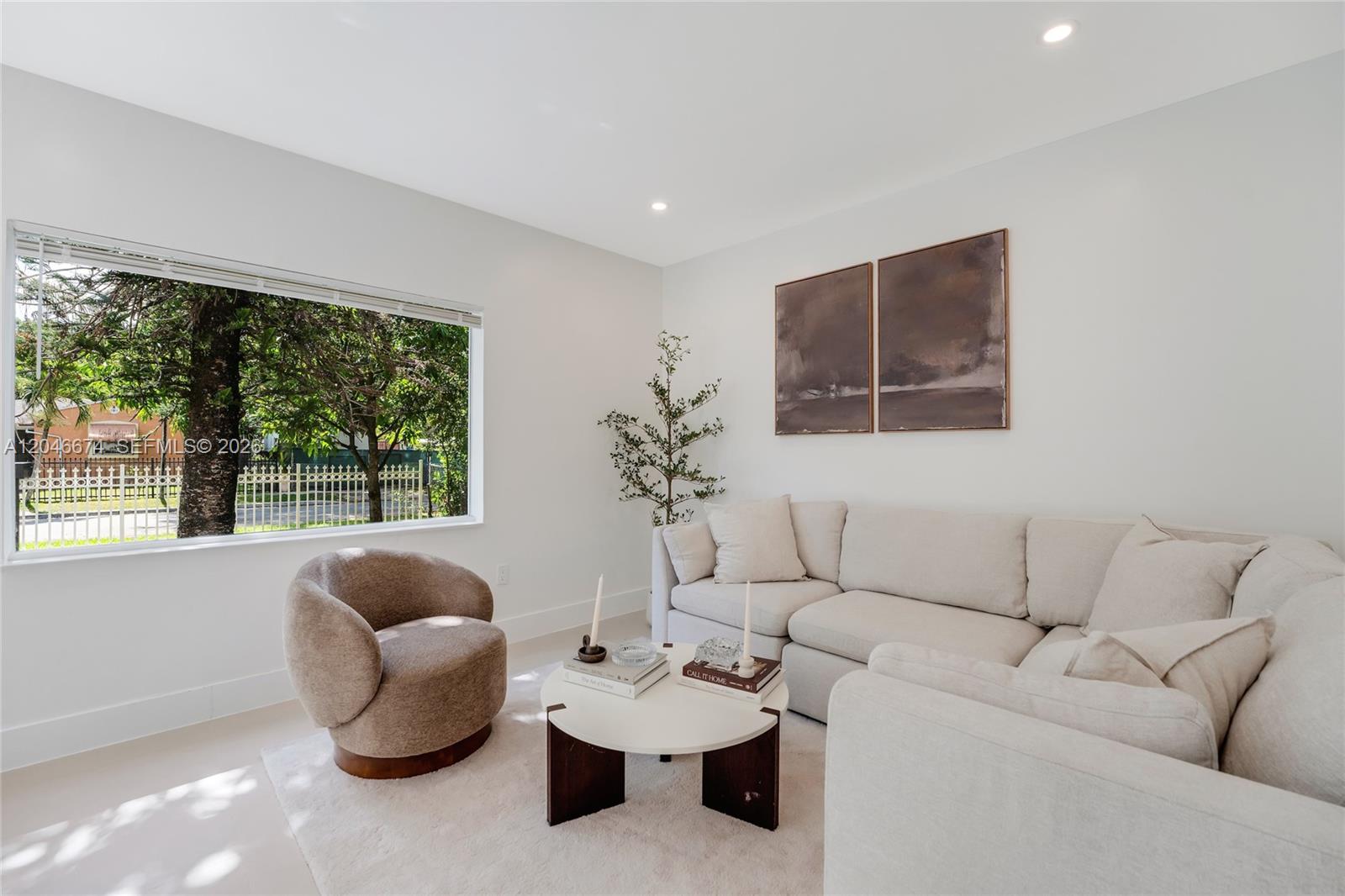 A living room features a beige sectional sofa, a round coffee table, and a swivel chair — 8318 NE 3rd Ct, Miami FL 33138, MIAMI, FL