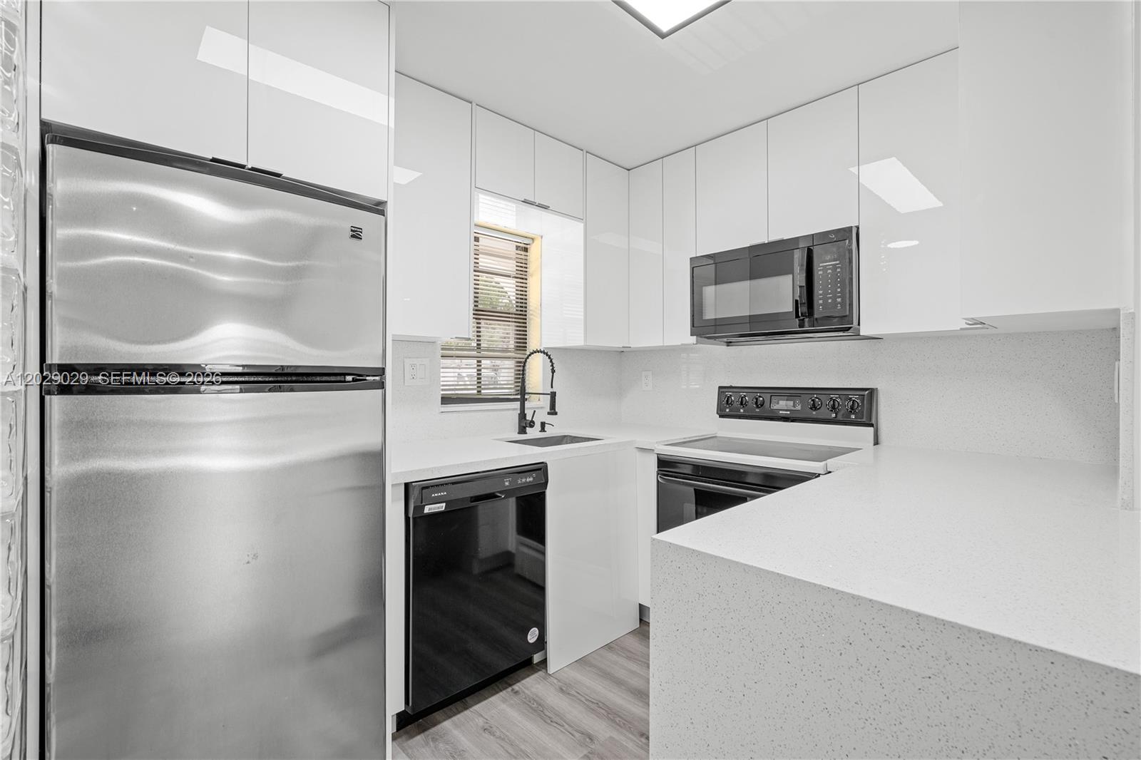 A modern kitchen features white cabinets, stainless steel appliances, and white quartz countertops — 12035 SW 18th St # 48, Miami FL 33175, MIAMI, FL