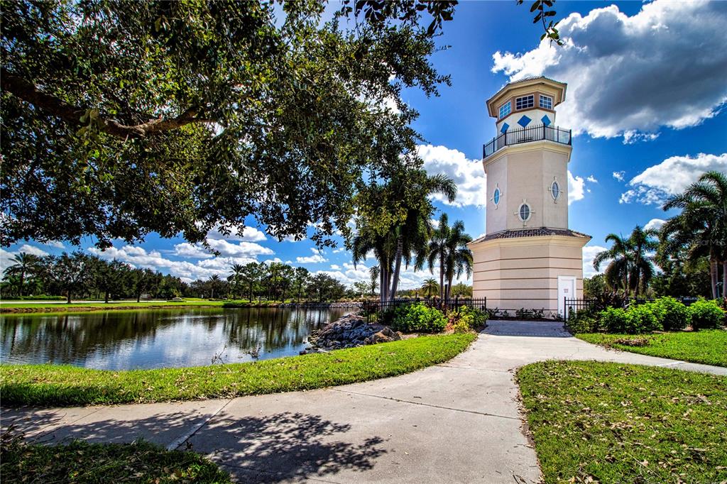 A decorative lighthouse stands beside a pond in a landscaped park area — 267 HERITAGE ISLES WAY, BRADENTON, FL