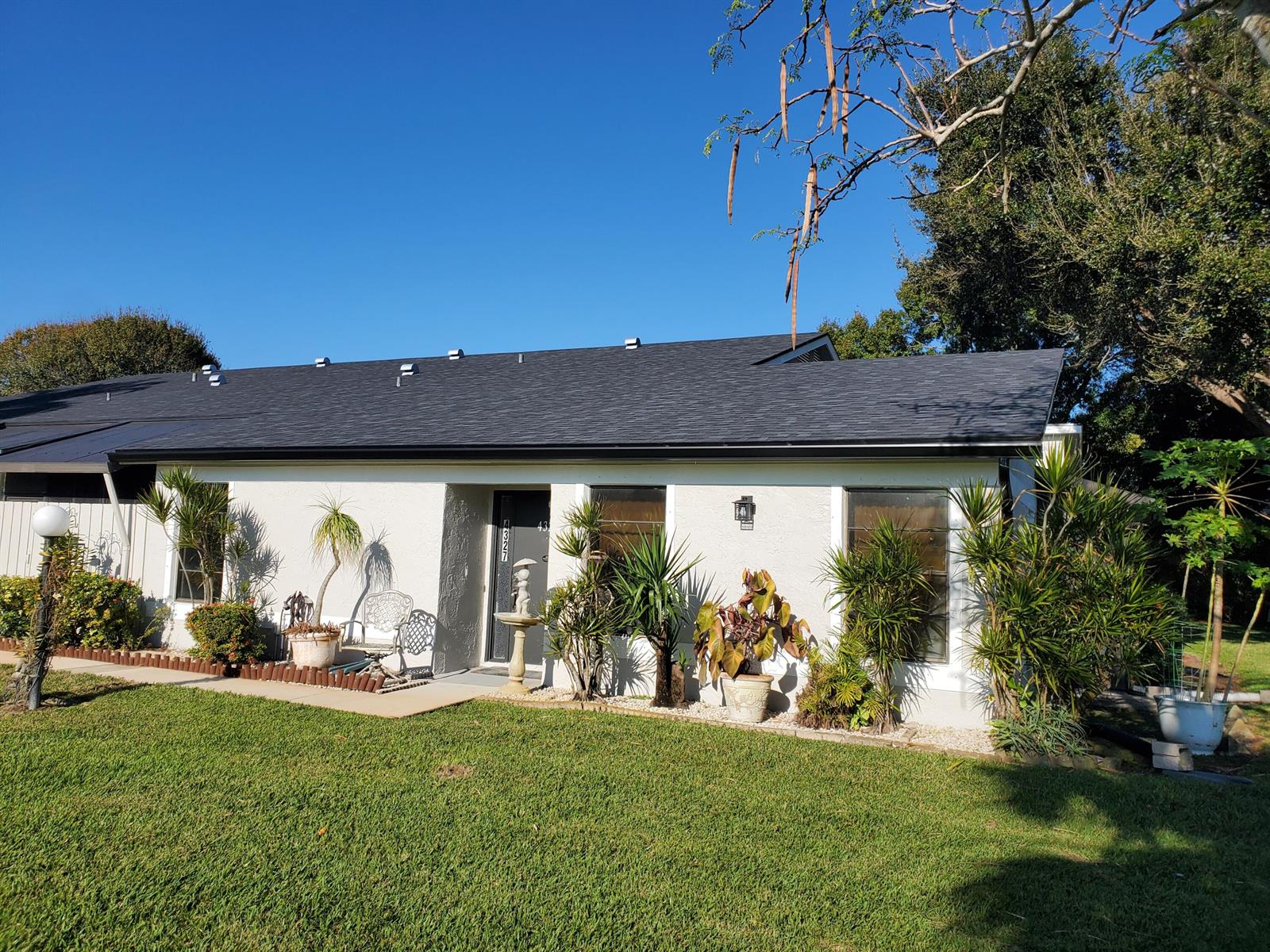 A single-story house with a white stucco exterior, dark shingled roof, and landscaped front yard — 4327 Willow Brook Circle, West Palm Beach FL 33417, WEST PALM BEACH, FL