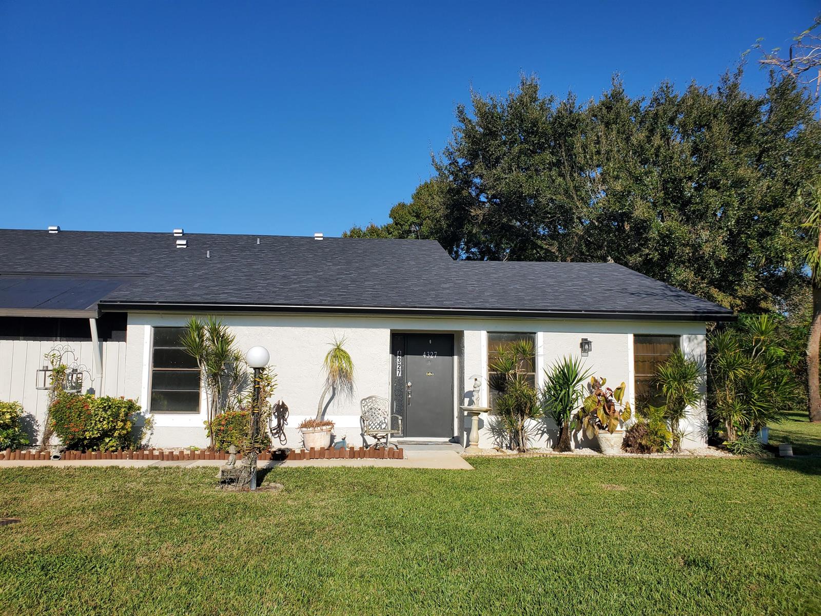 A single-story white house with a dark roof, front door, and landscaped yard — 4327 Willow Brook Circle, West Palm Beach FL 33417, WEST PALM BEACH, FL
