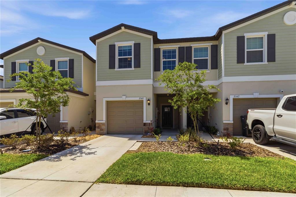 A row of two-story townhomes with beige stucco, green siding, and attached garages — 2549 SUNRAY VENUS WAY, RUSKIN, FL