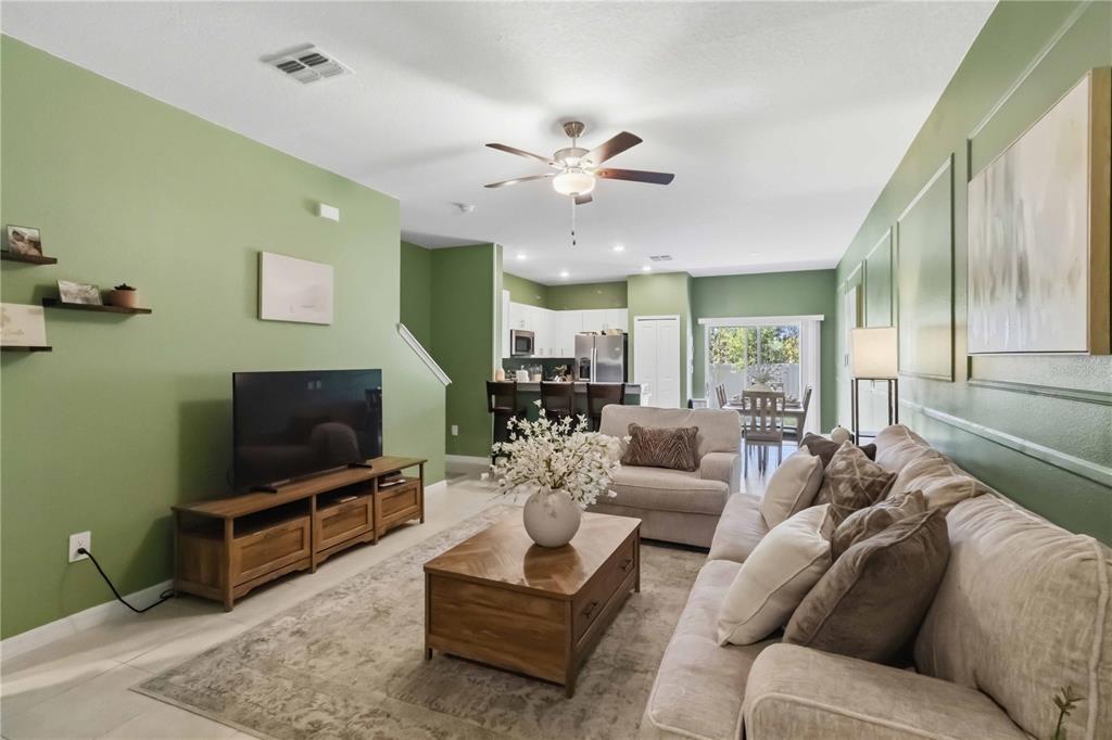 A living room features sage green walls, a beige sofa, and a wooden coffee table — 2549 SUNRAY VENUS WAY, RUSKIN, FL