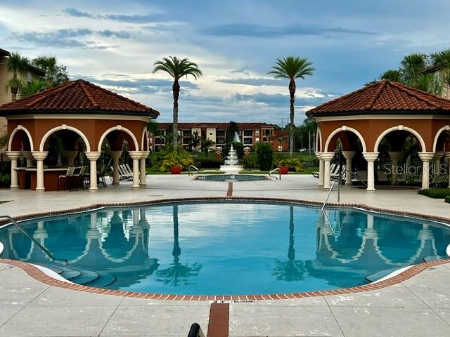 A swimming pool sits between two open-air gazebos with palm trees and apartment buildings behind — 2701 ORLANDO WEST DRIVE, ORLANDO, FL