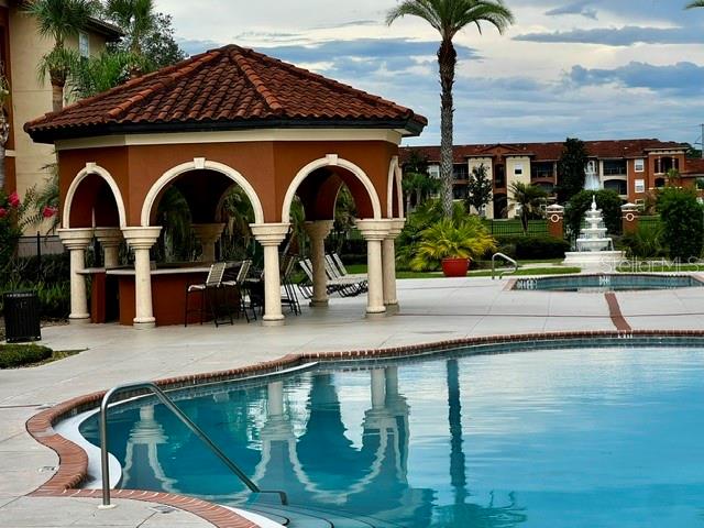 A swimming pool sits in front of a covered outdoor pavilion with arched openings — 2701 ORLANDO WEST DRIVE, ORLANDO, FL
