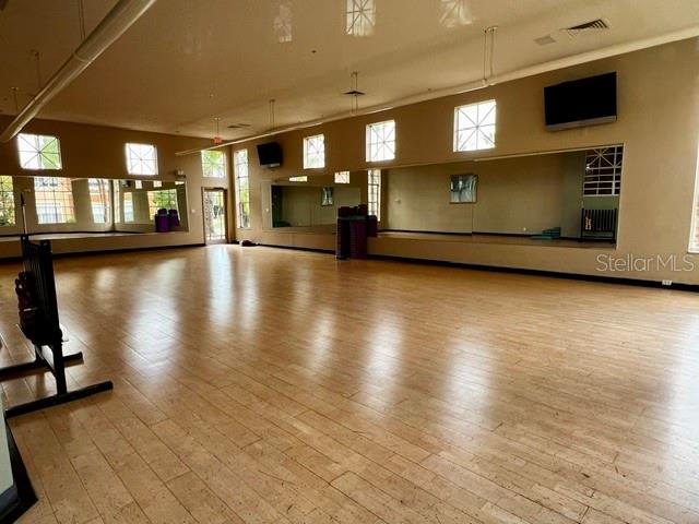 A spacious fitness studio features light wood flooring, mirrored walls, and large windows — 2701 ORLANDO WEST DRIVE, ORLANDO, FL