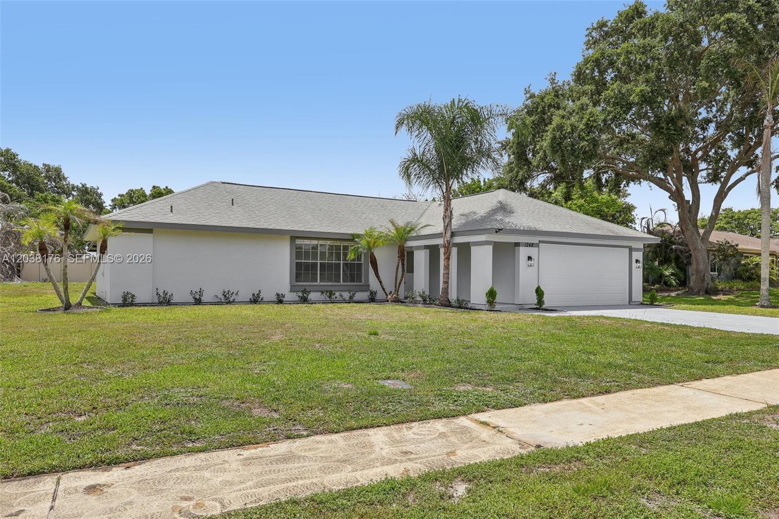 A single-story house with a white exterior, a two-car garage, and palm trees in front — 1248 Riviera, Palm Bay FL 32905, PALM BAY, FL