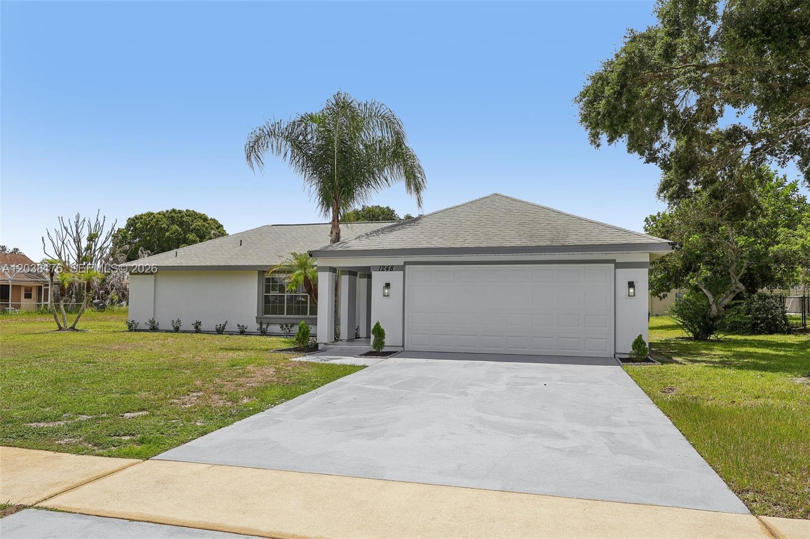 A single-story house with a white exterior, a two-car garage, and a concrete driveway — 1248 Riviera, Palm Bay FL 32905, PALM BAY, FL