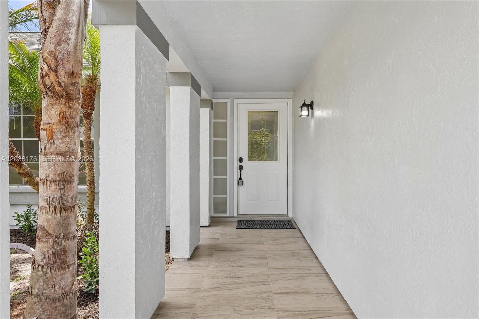 A covered entryway features white stucco columns, a tiled floor, and a white front door — 1248 Riviera, Palm Bay FL 32905, PALM BAY, FL