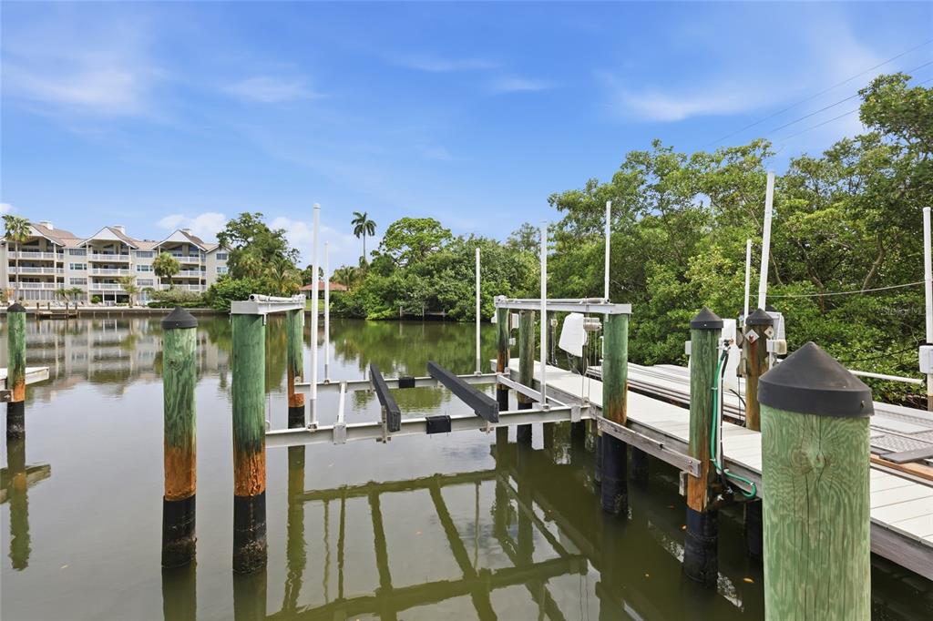 A boat lift sits in a calm canal next to a wooden dock and mangroves — 1798 LINCOLN PARK CIRCLE, SARASOTA, FL