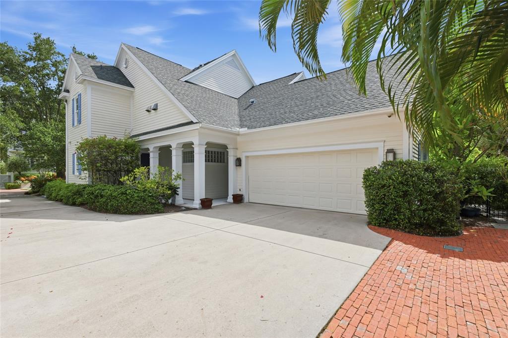 A two-story house with light siding, a two-car garage, and a brick-paved driveway — 1798 LINCOLN PARK CIRCLE, SARASOTA, FL