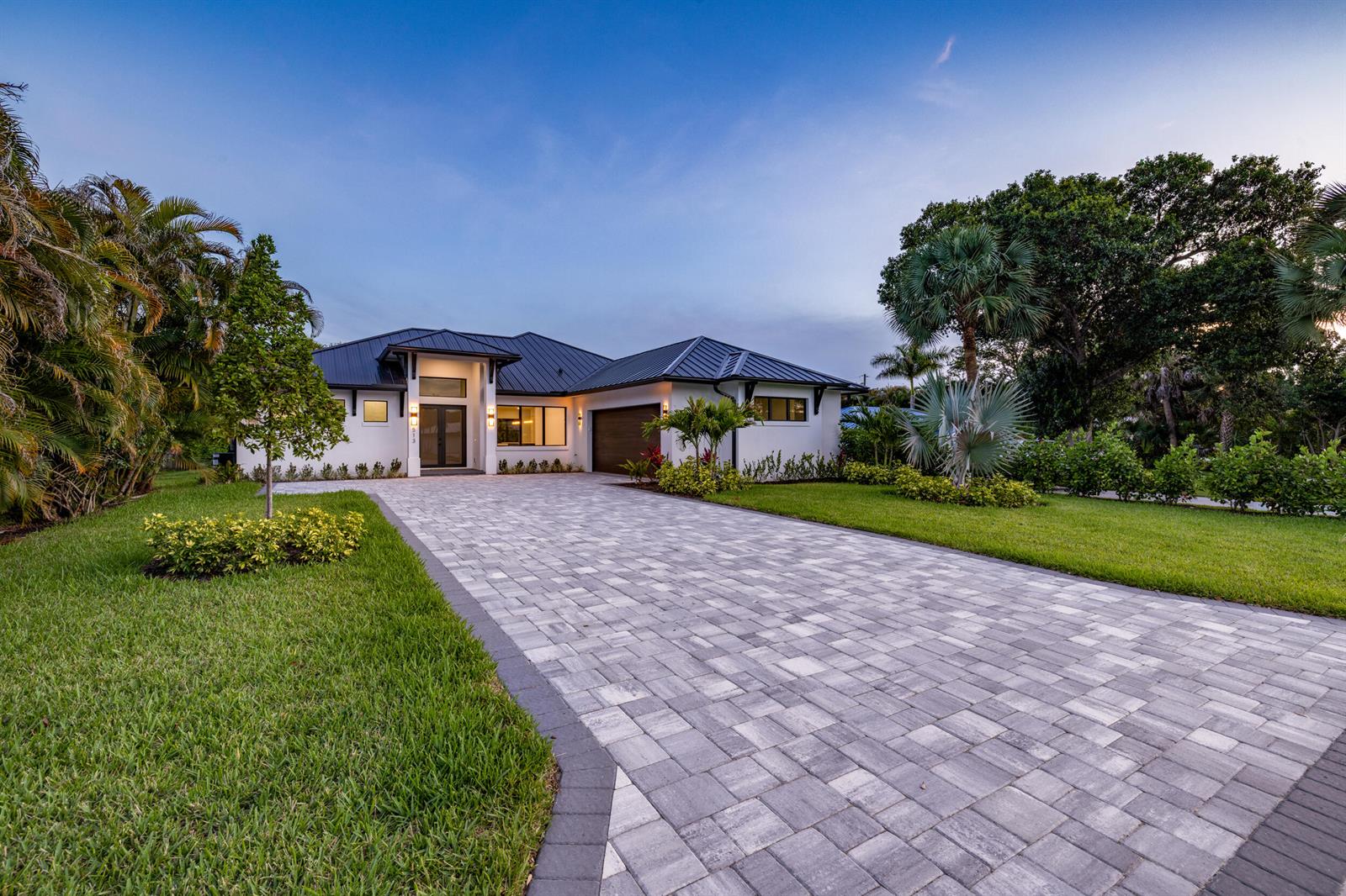 A modern single-story house with a metal roof and a paved driveway at dusk — 513 SW South Carolina Drive, Stuart FL 34994, STUART, FL