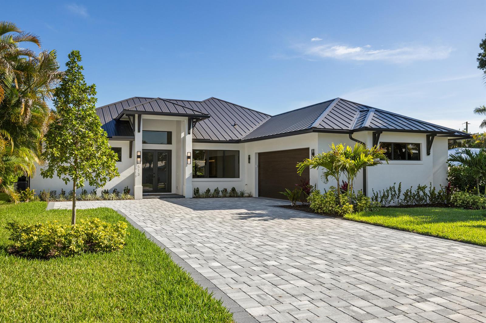 A modern single-story house with a metal roof, white stucco walls, and a paved driveway — 513 SW South Carolina Drive, Stuart FL 34994, STUART, FL