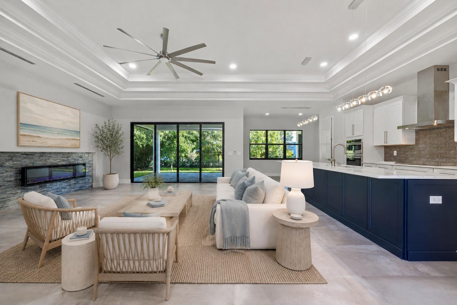 A modern open-concept living room and kitchen featuring a blue island and stone fireplace — 513 SW South Carolina Drive, Stuart FL 34994, STUART, FL
