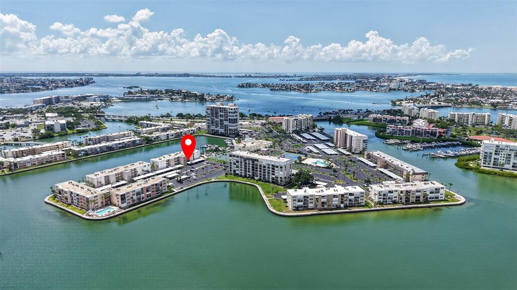 An aerial view shows a waterfront residential complex with multiple buildings surrounded by a bay — 7625 SUN ISLAND DRIVE S UNIT 103, SOUTH PASADENA, FL