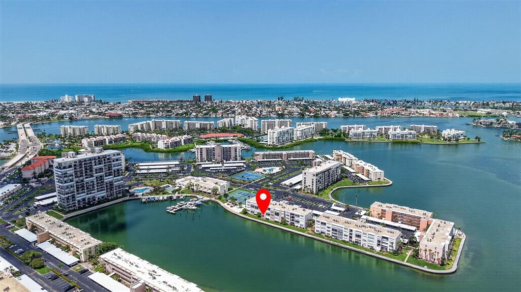 An aerial view shows a waterfront condominium complex with a red location marker — 7625 SUN ISLAND DRIVE S UNIT 103, SOUTH PASADENA, FL
