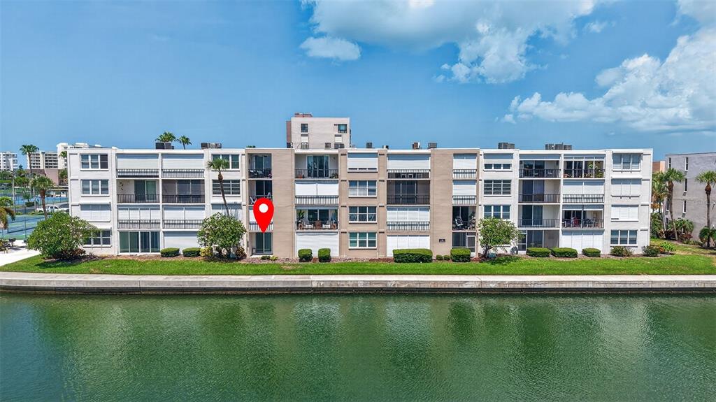 An exterior view of a multi-story apartment building situated along a waterfront canal — 7625 SUN ISLAND DRIVE S UNIT 103, SOUTH PASADENA, FL