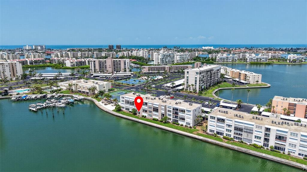An aerial view shows waterfront apartment buildings with a red location pin on one structure — 7625 SUN ISLAND DRIVE S UNIT 103, SOUTH PASADENA, FL