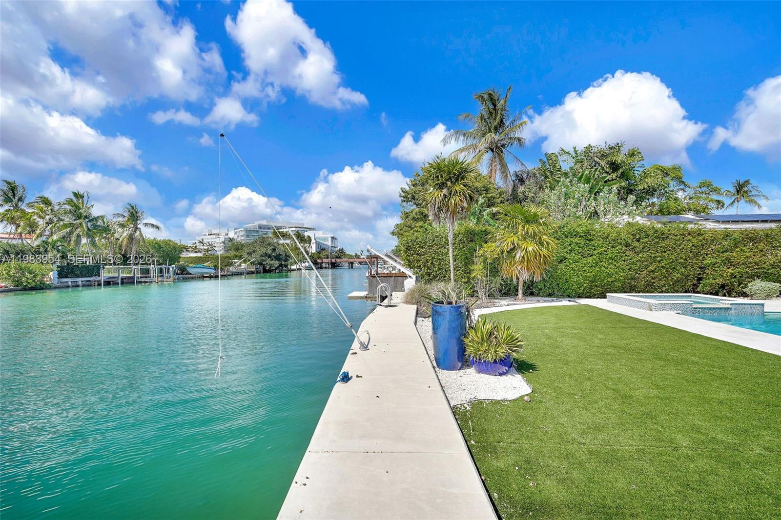 A concrete dock extends along a canal next to a grassy lawn and swimming pool — 4560 Prairie Ave, Miami Beach FL 33140, MIAMI BEACH, FL