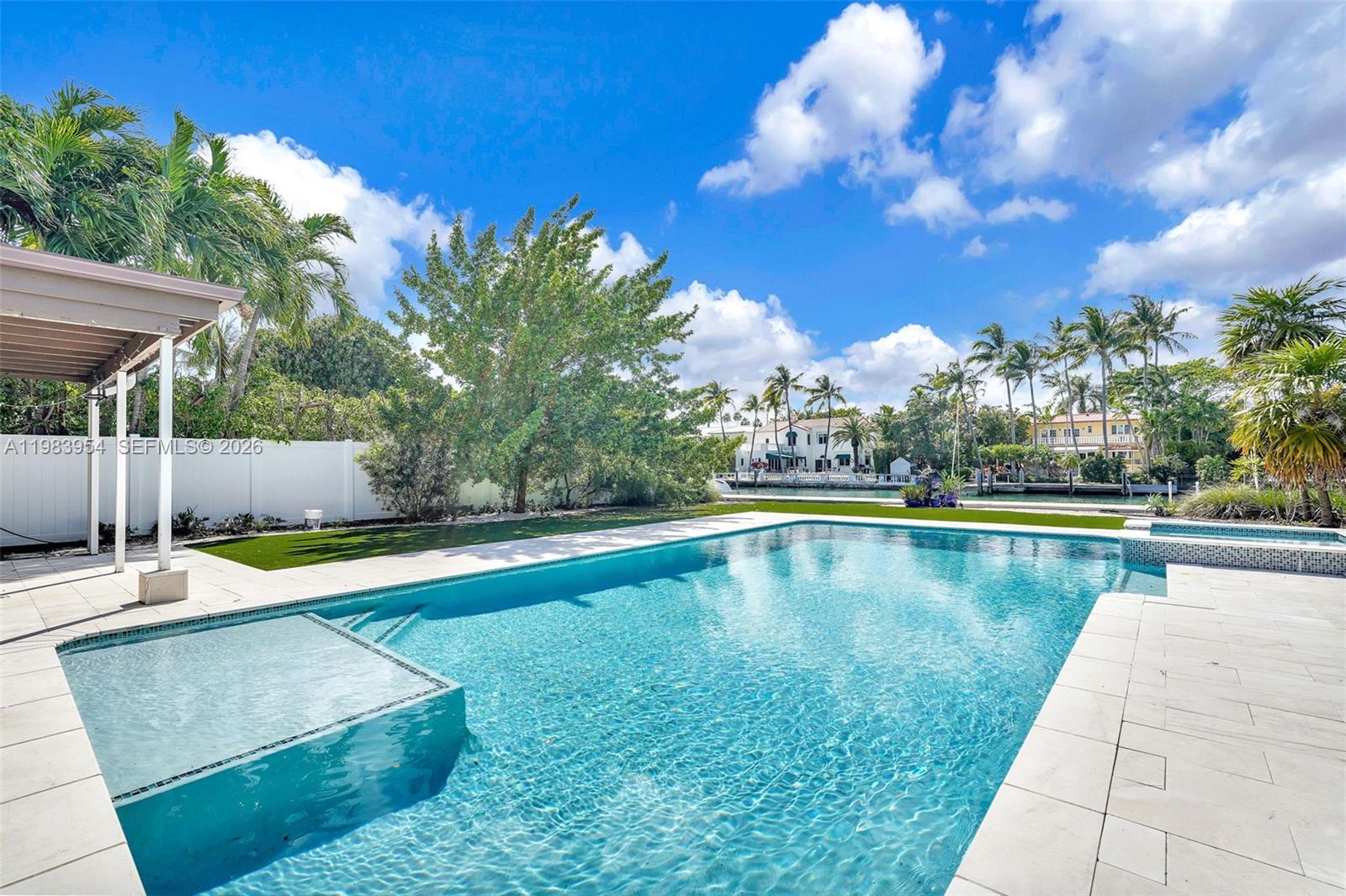 A backyard features a rectangular swimming pool with a tanning ledge and a canal view — 4560 Prairie Ave, Miami Beach FL 33140, MIAMI BEACH, FL
