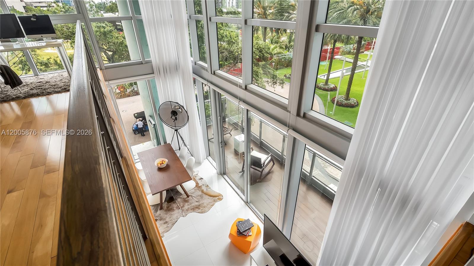 A high-angle view of a two-story living space with floor-to-ceiling windows and a dining area — 90 SW 3rd St # 308, Miami FL 33130, MIAMI, FL