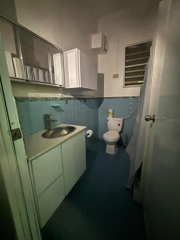 A bathroom features a vanity with a silver sink, blue tiled walls, and a toilet — 26 MANUEL CORCHADO UNIT ! A, AGUADILLA, PR