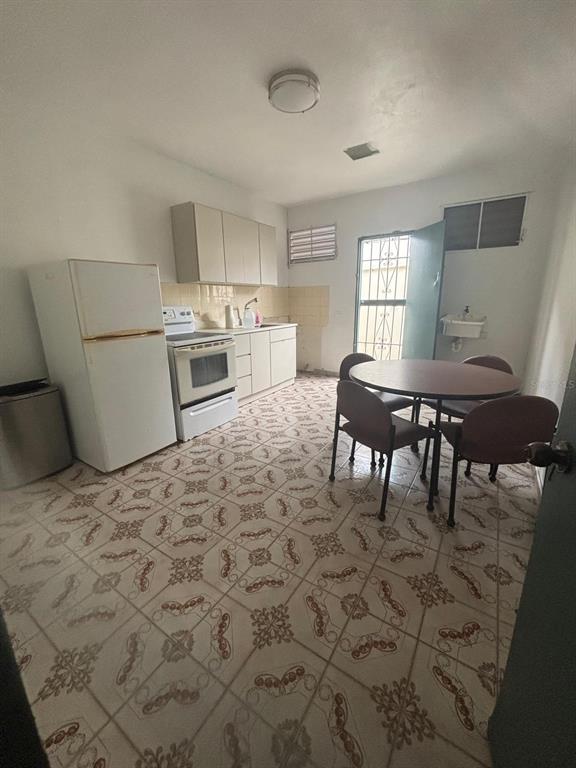 A kitchen with patterned tile flooring, a dining table, and white appliances — 26 MANUEL CORCHADO UNIT ! A, AGUADILLA, PR