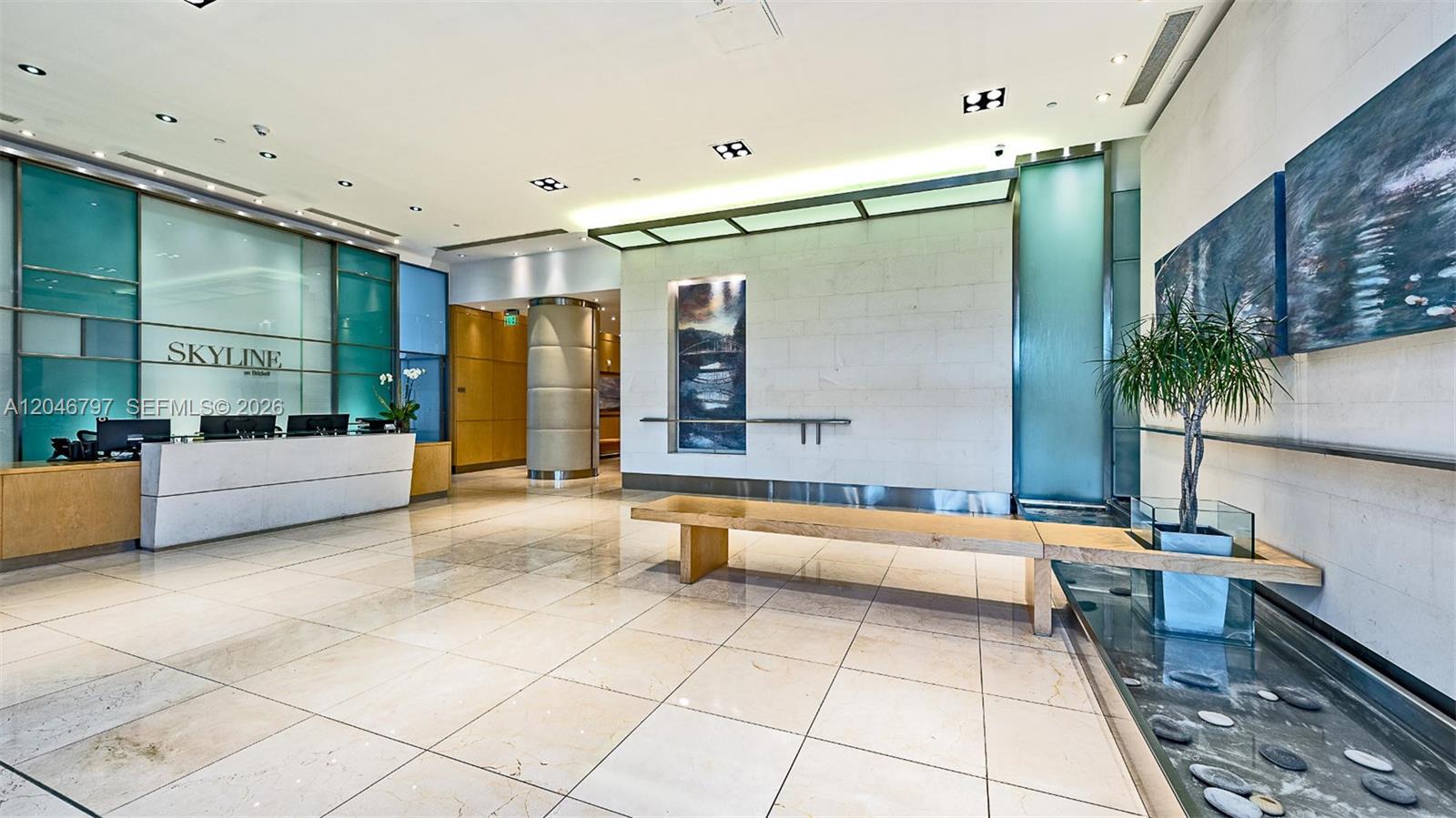 A bathroom features marble-tiled walls, a glass-enclosed shower, a white toilet, and built-in shelving — 2101 Brickell Ave # 1501, Miami FL 33129, MIAMI, FL
