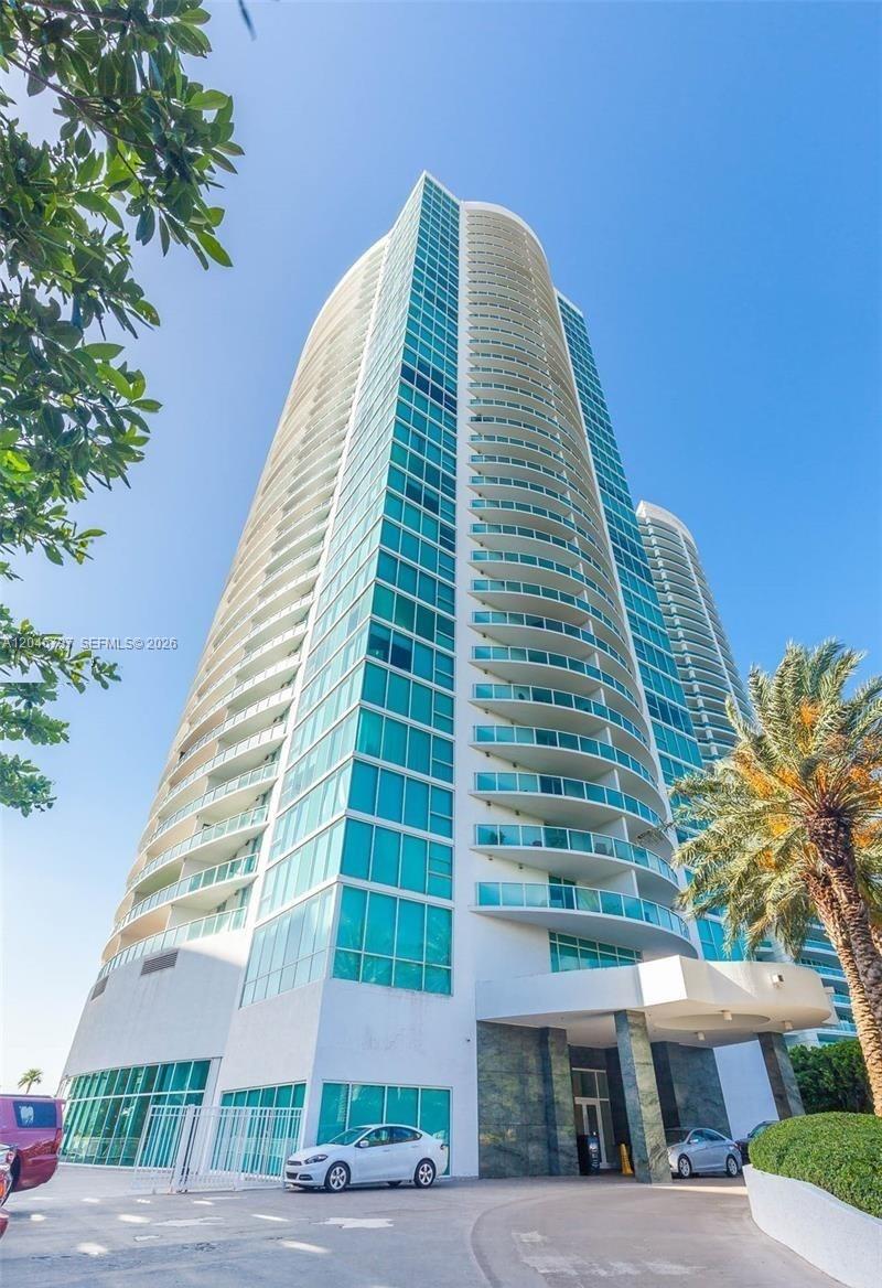 A living room with wood flooring features a dark sofa, dining area, and display cabinet — 2101 Brickell Ave # 1501, Miami FL 33129, MIAMI, FL