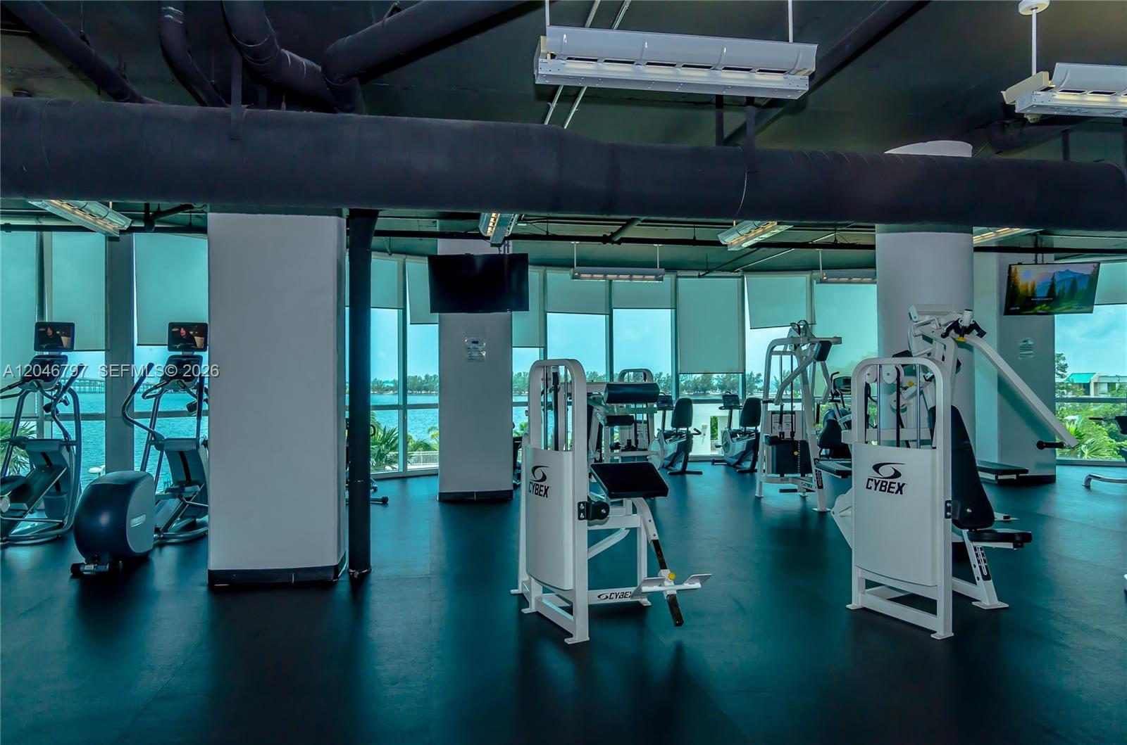 A room with hardwood floors and floor-to-ceiling windows overlooks a city with lush greenery — 2101 Brickell Ave # 1501, Miami FL 33129, MIAMI, FL