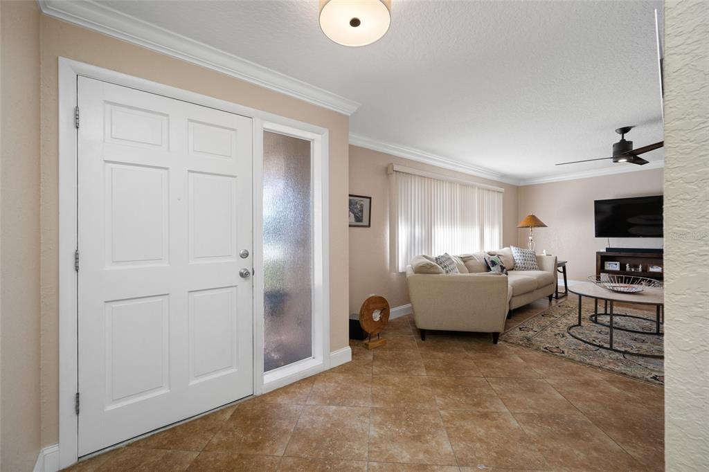 An entryway with tile flooring leads into a living room featuring a sofa and television — 12957 90TH TERRACE, SEMINOLE, FL