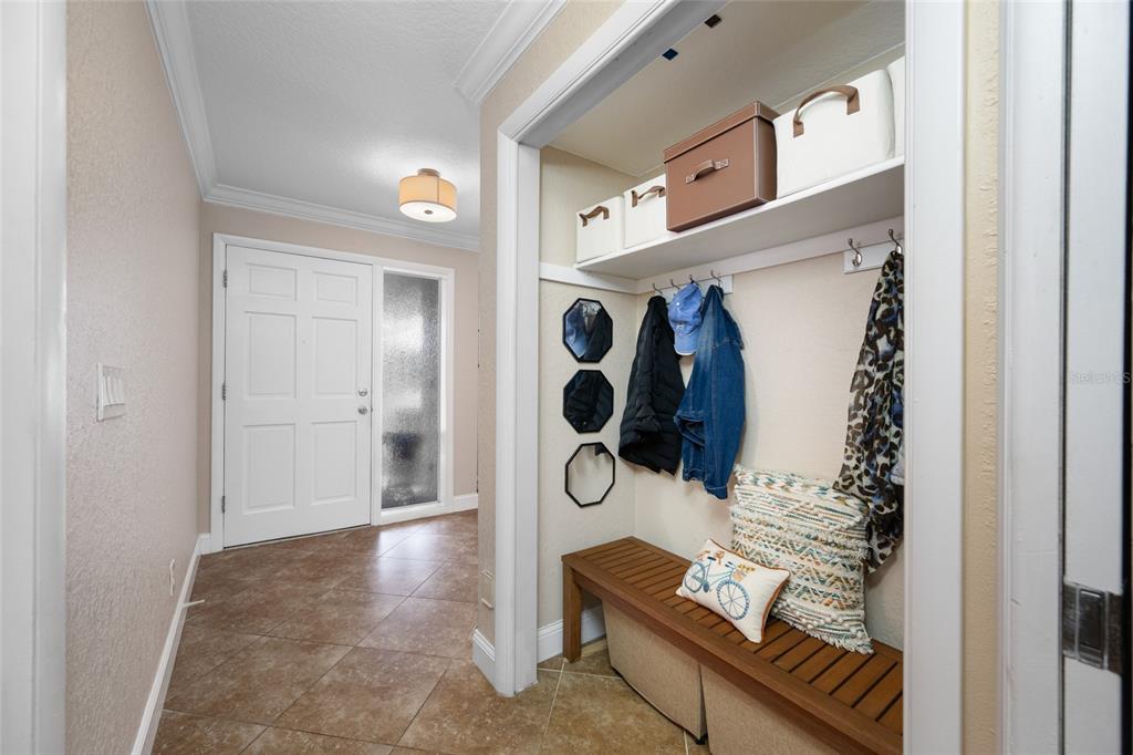 A mudroom area with a wooden bench, coat hooks, and storage bins near an entryway — 12957 90TH TERRACE, SEMINOLE, FL