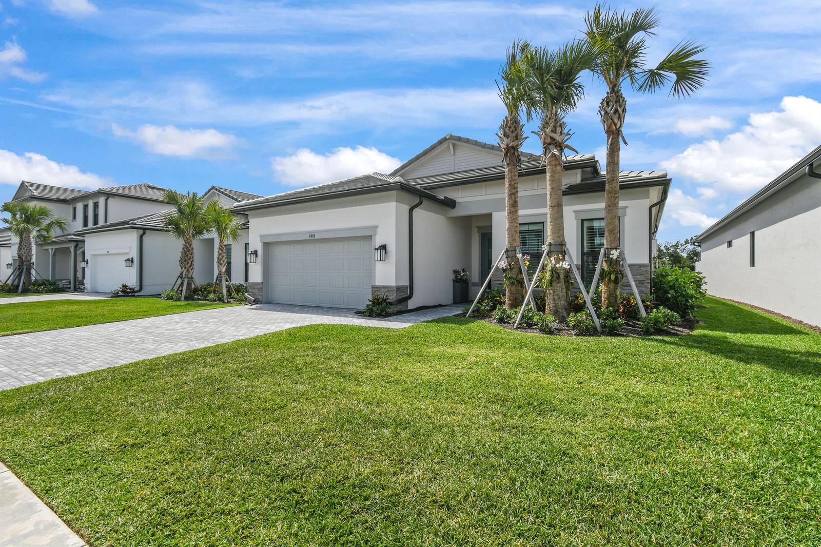A single-story house with a gray garage, white stucco exterior, and three palm trees — 9358 Cape Honey Bee Lane, Lake Worth FL 33467, LAKE WORTH, FL