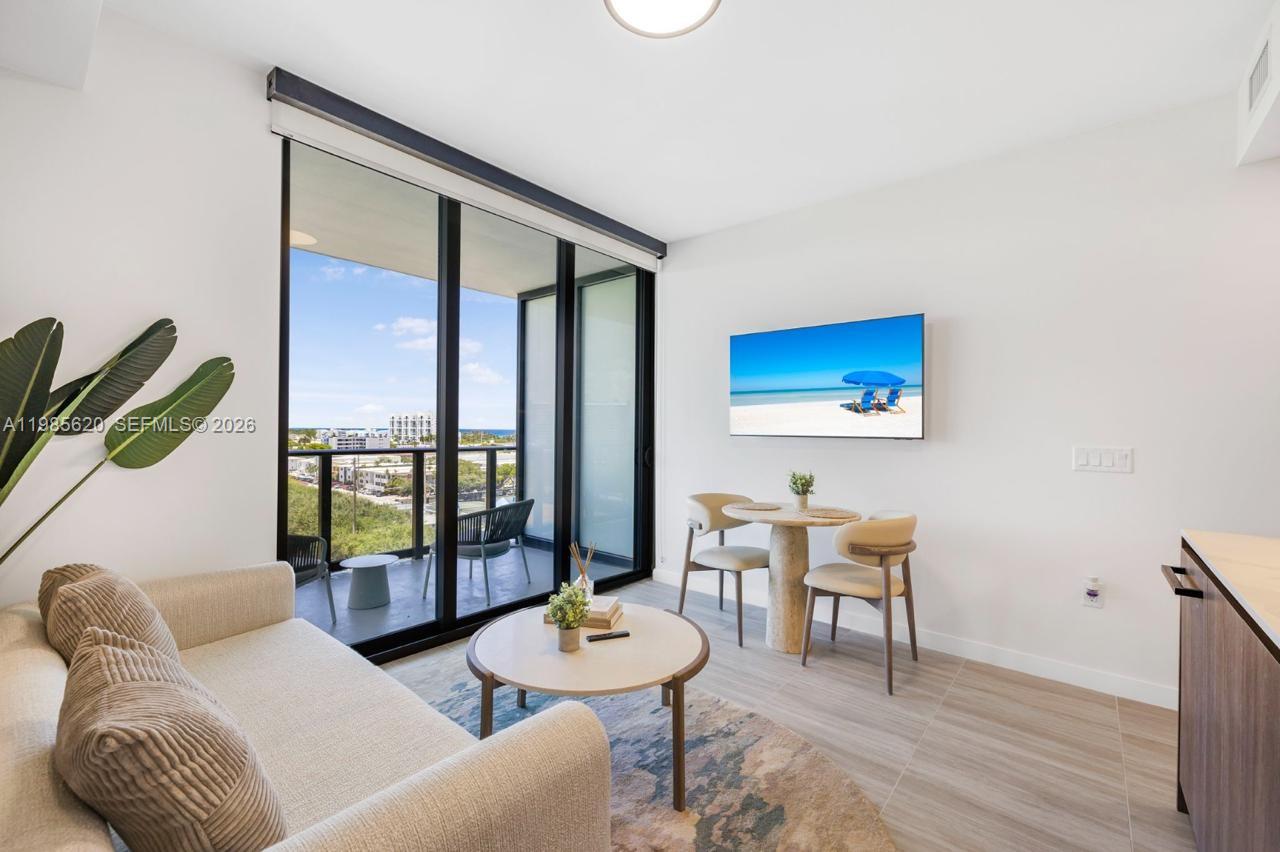 A modern living area features a sofa, a small dining set, and a balcony view — 580 72nd St # 613, Miami Beach FL 33141, MIAMI BEACH, FL