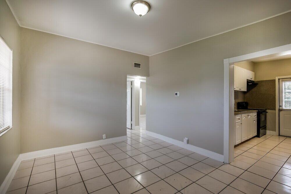A dining area with light-colored tile flooring, beige walls, and an adjacent kitchen — MIAMI, FL