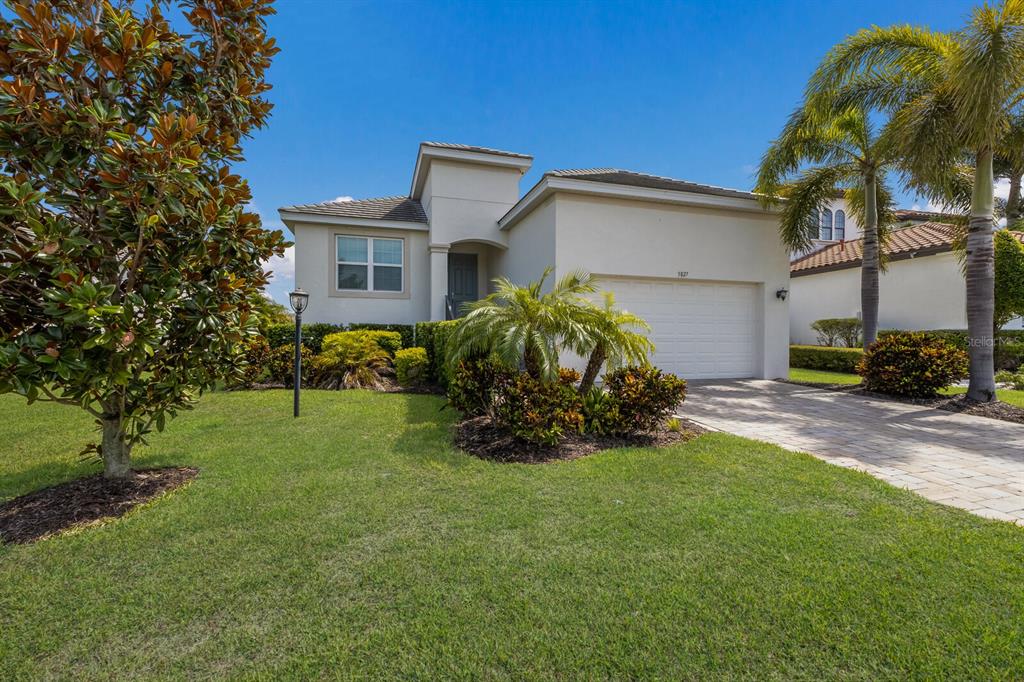 A single-story house with a white stucco exterior, a two-car garage, and a paved driveway — 5827 INSPIRATION TERRACE, BRADENTON, FL