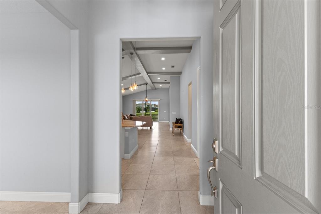 A view from an open front door into a tiled hallway leading to a living area — 5827 INSPIRATION TERRACE, BRADENTON, FL