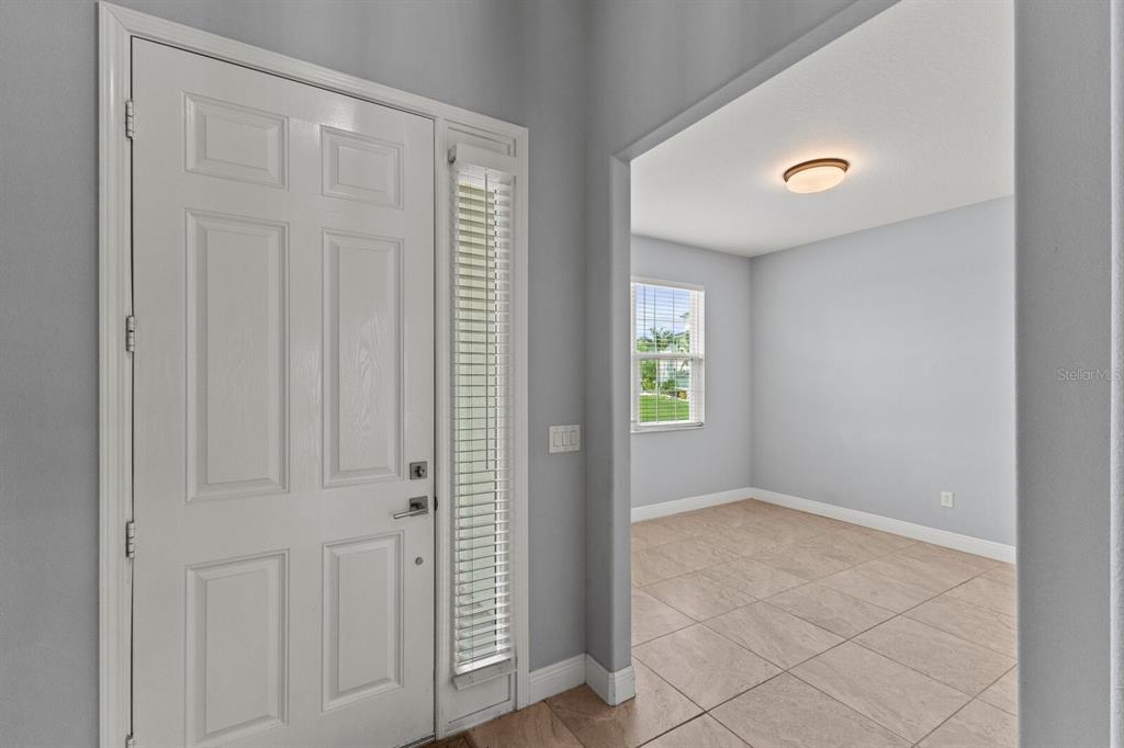 An entryway features a white front door with a sidelight and a tiled floor — 5827 INSPIRATION TERRACE, BRADENTON, FL