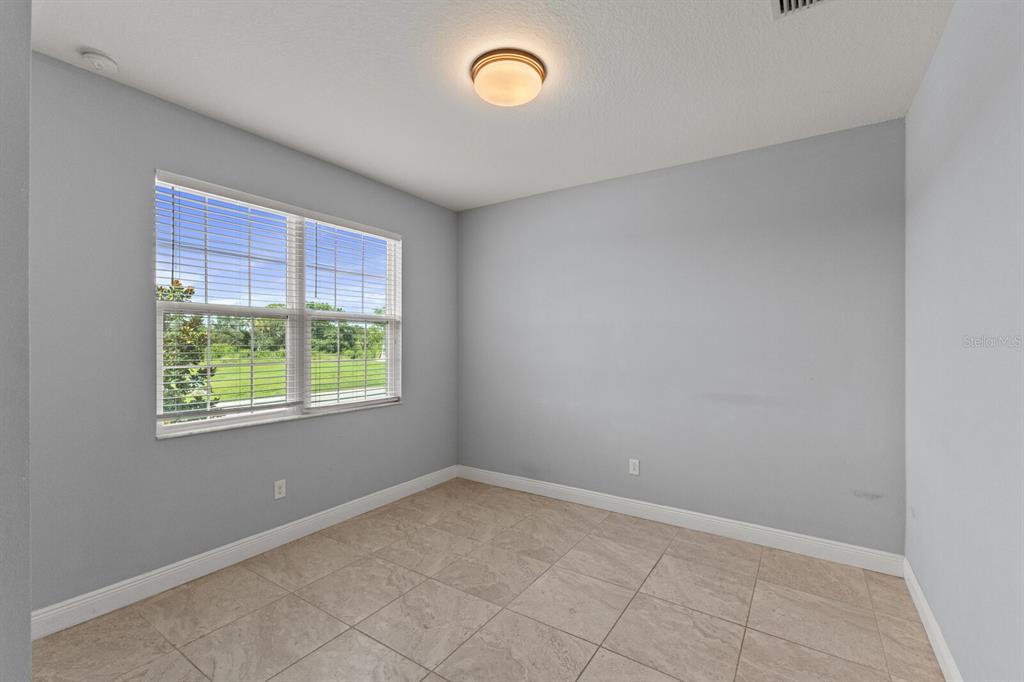 An empty room with light gray walls, tiled flooring, a ceiling light, and a window — 5827 INSPIRATION TERRACE, BRADENTON, FL