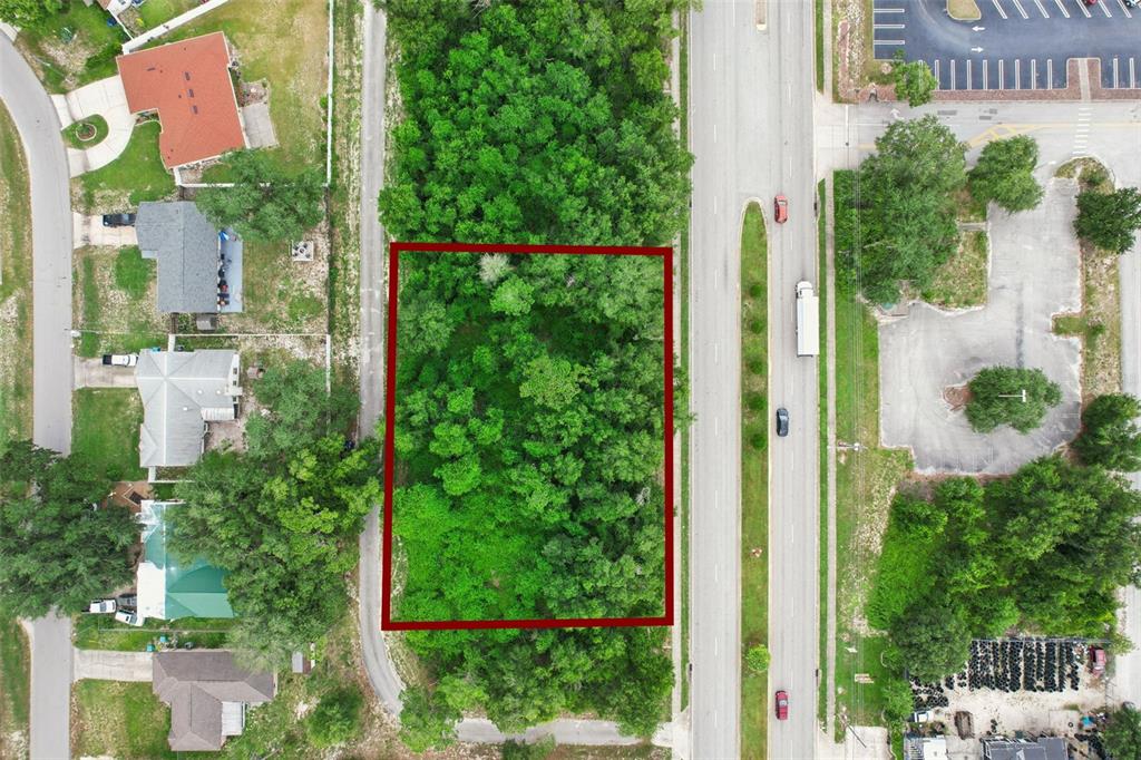 An aerial view shows a rectangular, tree-covered lot outlined in red next to a road — 2841 HOWLAND BOULEVARD, DELTONA, FL